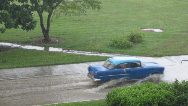 Blauer Oldtimer in Kuba ist trotz starkem Regen unterwegs.